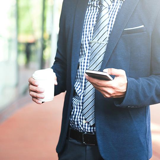 Why printing remains essential businessman holding a coffee and mobile phone